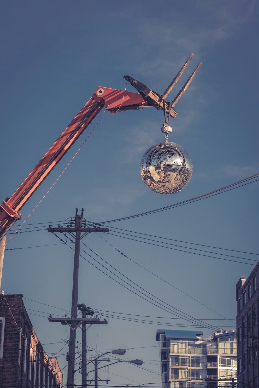 worm's-eye view photography of red and silver wrecking ball near electric post under clear blue sky