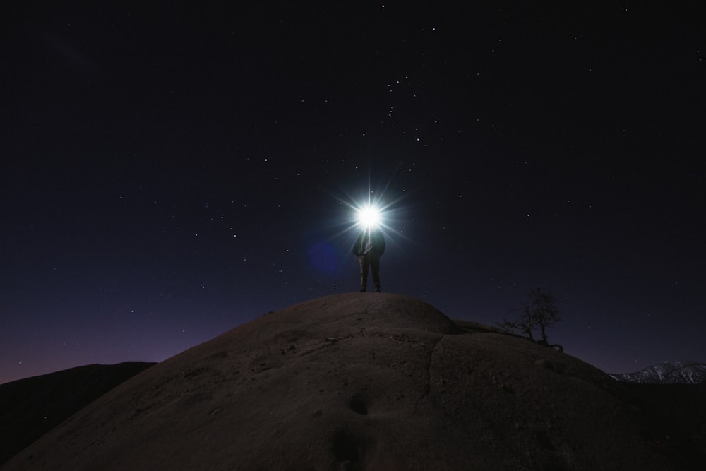 homme debout sur la montagne blanche tenant une lampe de poche