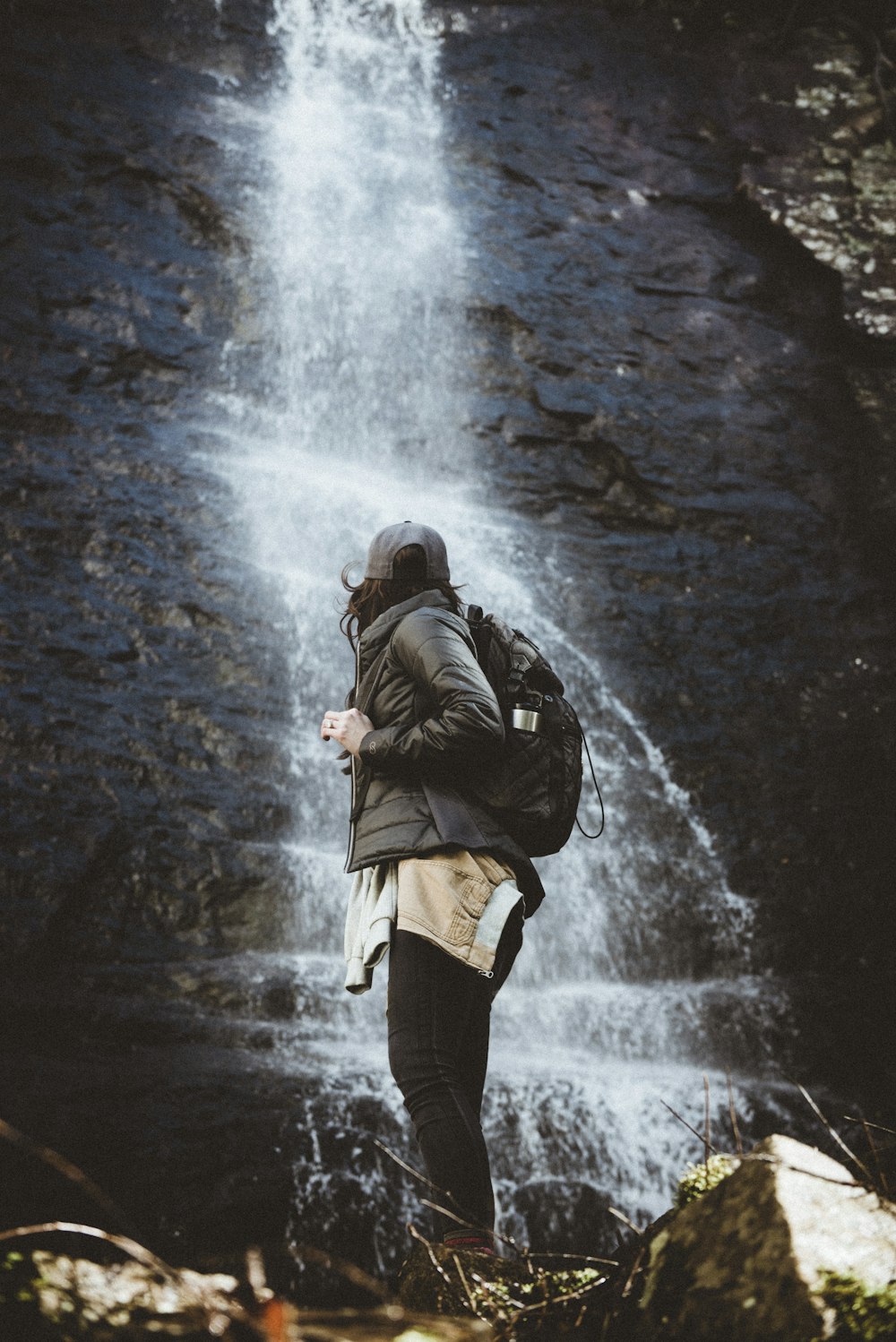 personne debout à côté des chutes d’eau