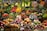 A vibrant market display filled with an assortment of fruits and vegetables, including apples, oranges, asparagus, eggplants, pumpkins, pineapples, and leafy greens. The produce is neatly organized and labeled, showcasing a variety of colors and textures.