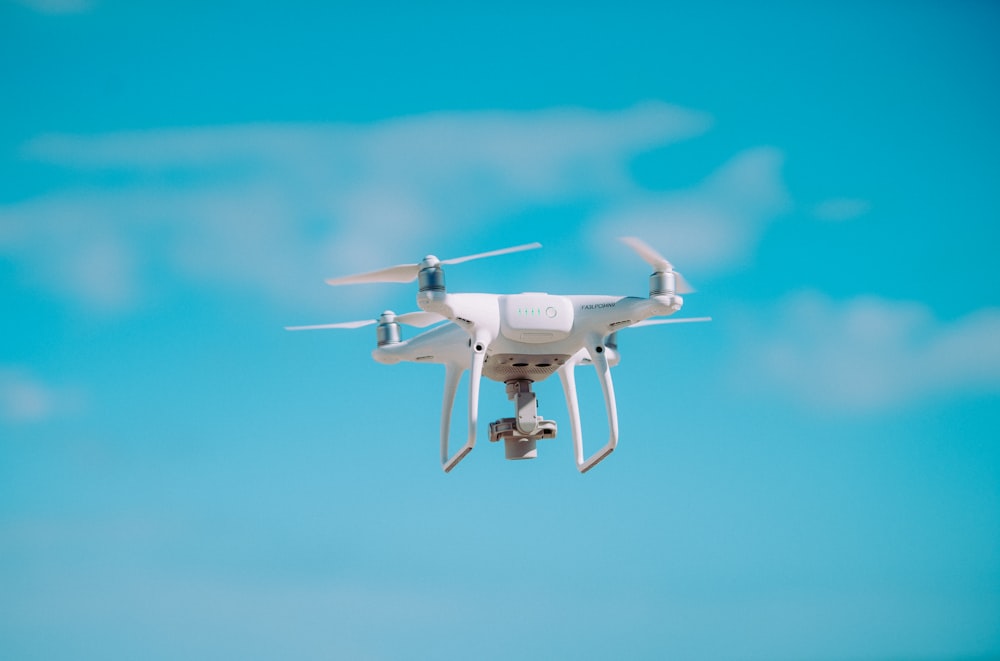 white quadcopter flying during daytime