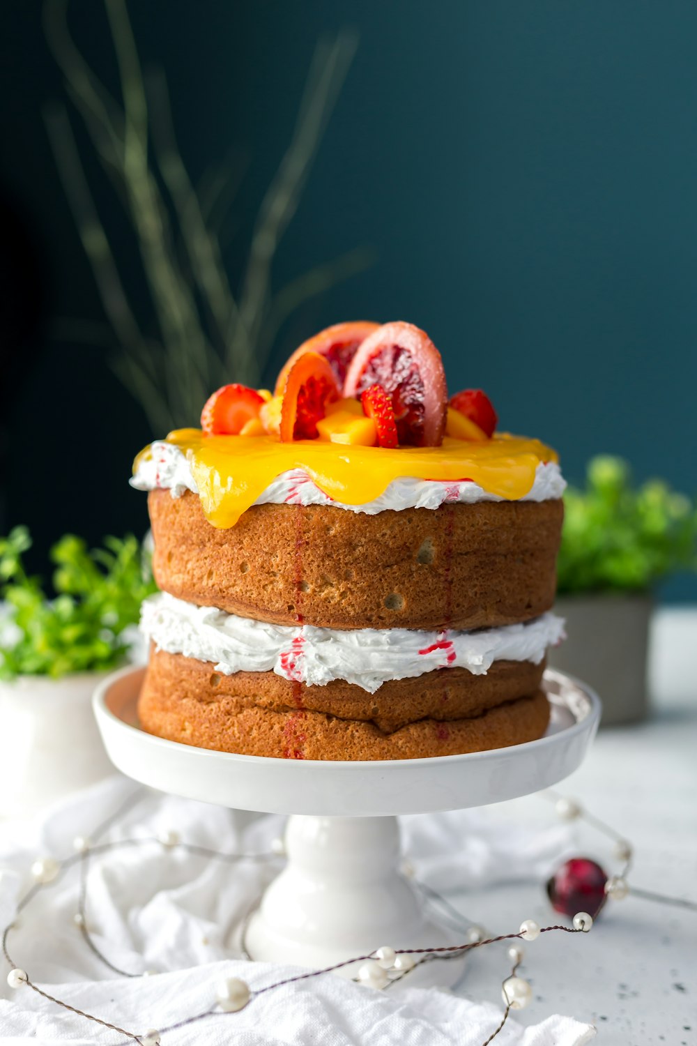 two-layered cake with citrus fruit and strawberry toppings