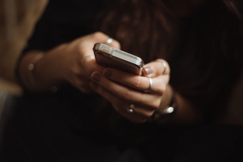 Hands holding a smartphone against a dark background