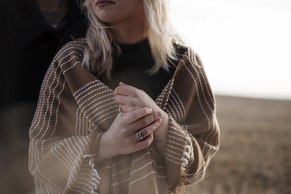 Femme couverte d’une écharpe marron avec les mains croisées