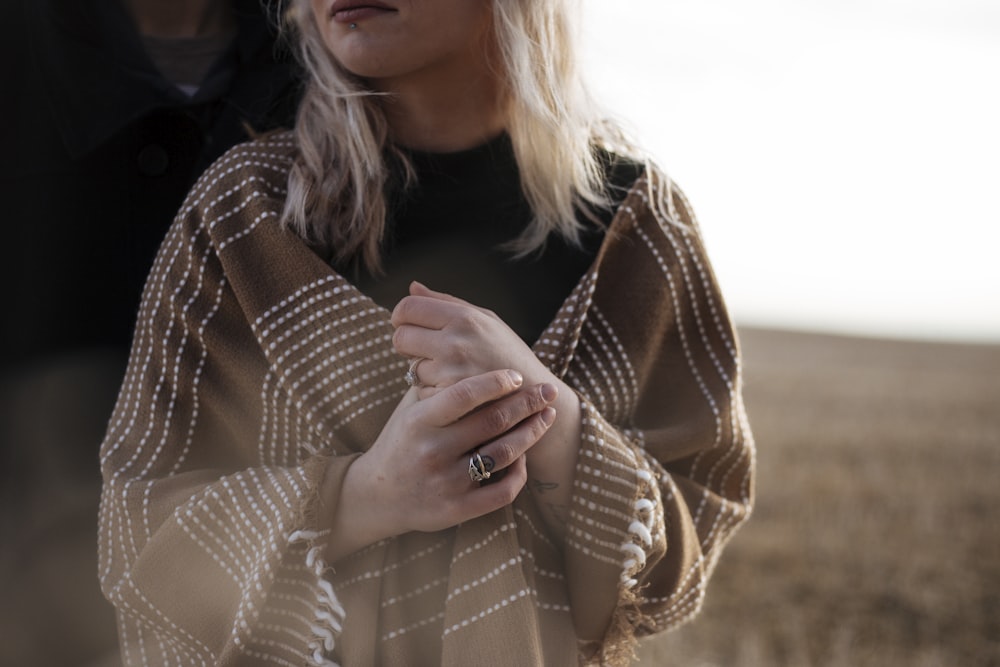 mulher coberta de lenço marrom com mãos cruzadas