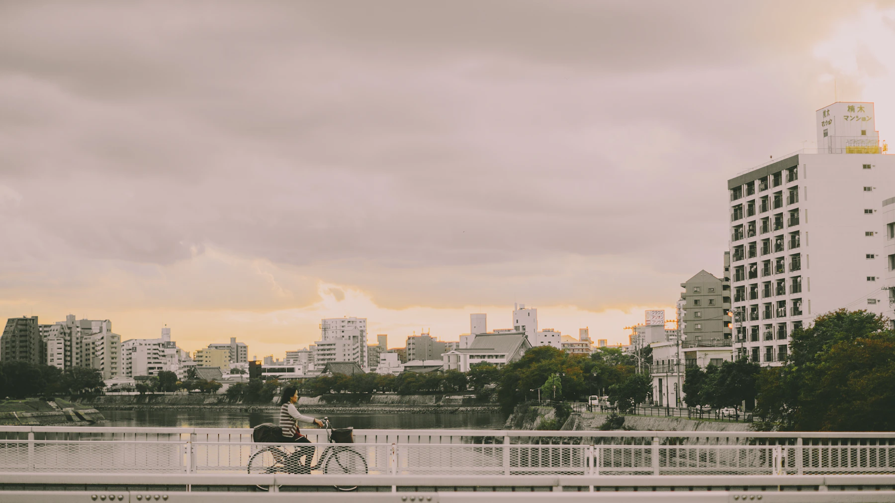 A cyclist crossing a bridge over one of Hiroshima's rivers at sunset