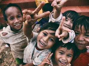 five children smiling while doing peace hand sign