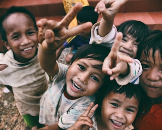 five children smiling while doing peace hand sign