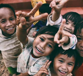 five children smiling while doing peace hand sign