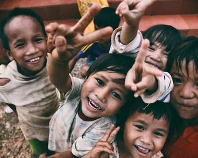 five children smiling while doing peace hand sign