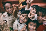 five children smiling while doing peace hand sign