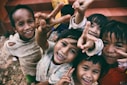 five children smiling while doing peace hand sign