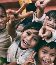 five children smiling while doing peace hand sign