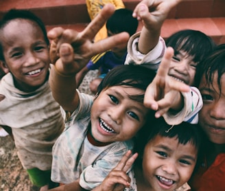 five children smiling while doing peace hand sign