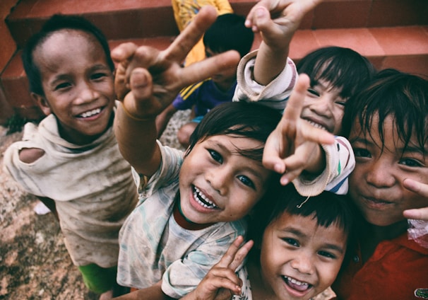 five children smiling while doing peace hand sign