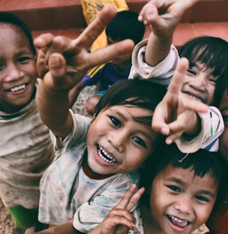 five children smiling while doing peace hand sign