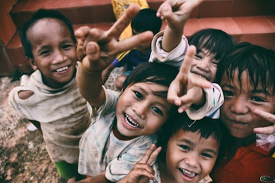 five children smiling while doing peace hand sign charity google meet background