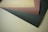 Four overlapping sheets of paper in different colors lie flat on a surface. The paper colors include light brown, dark brown, beige, and black.