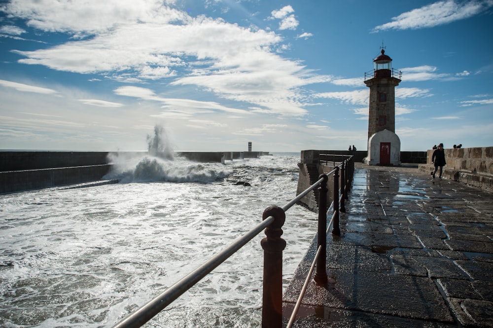 white lighthouse near body of water during daytime