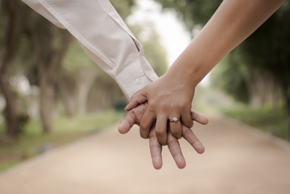 Flachfokusfotografie von zwei Personen, die Händchen halten
