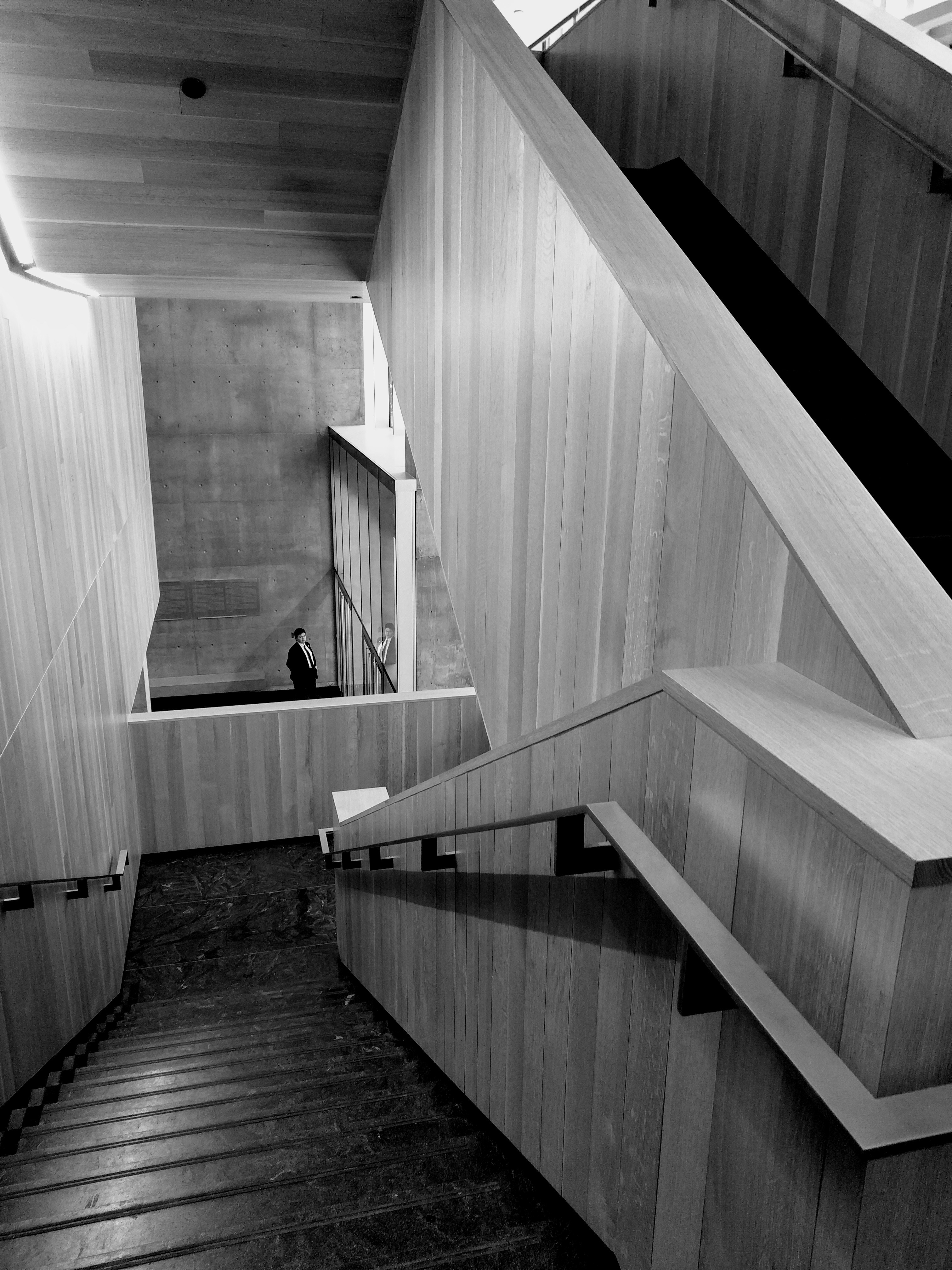 Lone executive standing at the top of a staircase in a grand corporate building