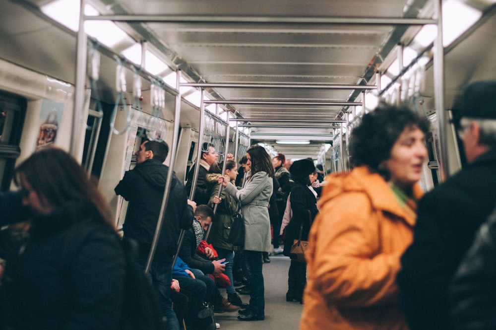 woman standing inside train surrounded by people