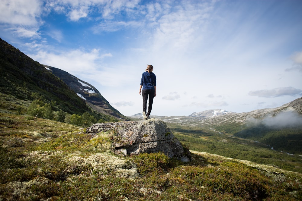 person standing on rock looking at mountain