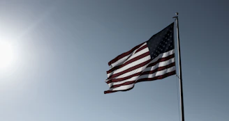 American flag waving gently against a clear blue sky.