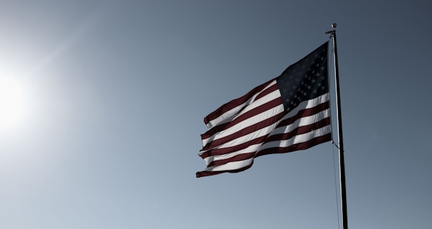 An American flag waving proudly against a clear blue sky during a sunny day.