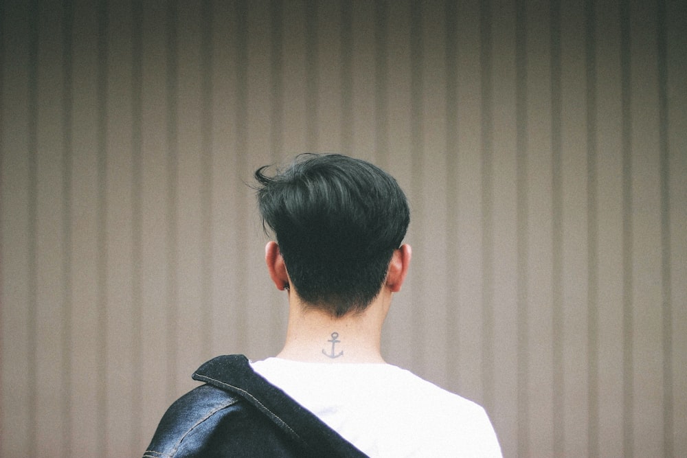 shallow focus photography of man facing white wall