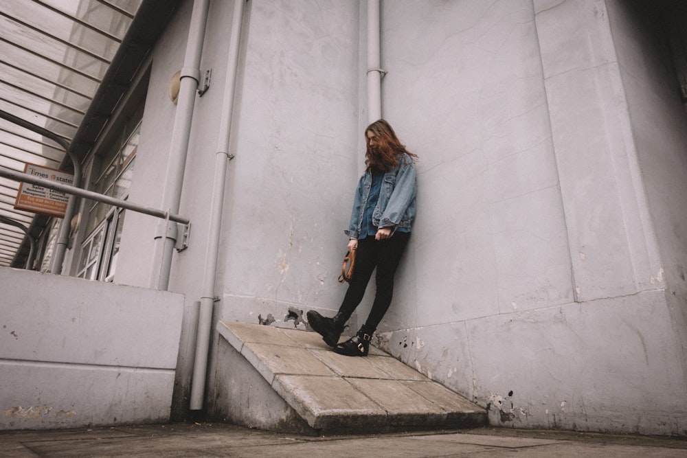 man leaning on gray concrete wall