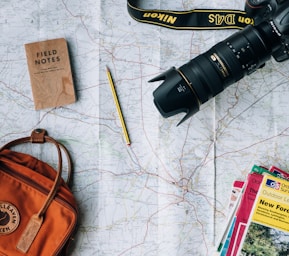 flat lay photography of camera, book, and bag