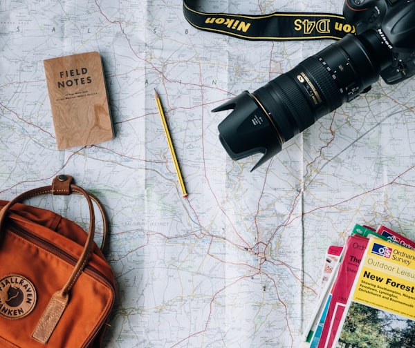 flat lay photography of camera, book, and bag