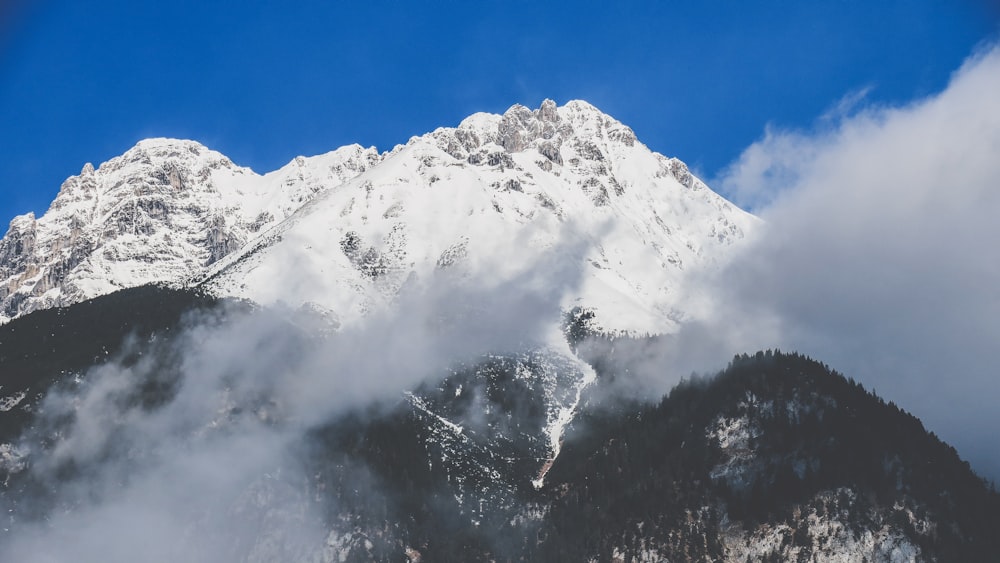 snowy mountain covered by clouds during daytime