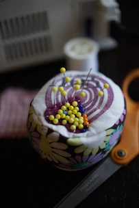 A colorful assortment of sewing tools including scissors, pins, and measuring tape on fabric.