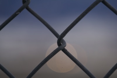Close-up of standard privacy tape woven through chain-link fence under sunlight.