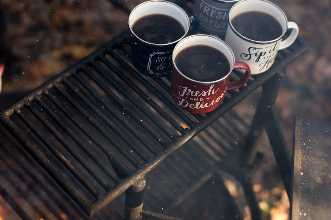 four assorted-color ceramic mugs on black grill frame,