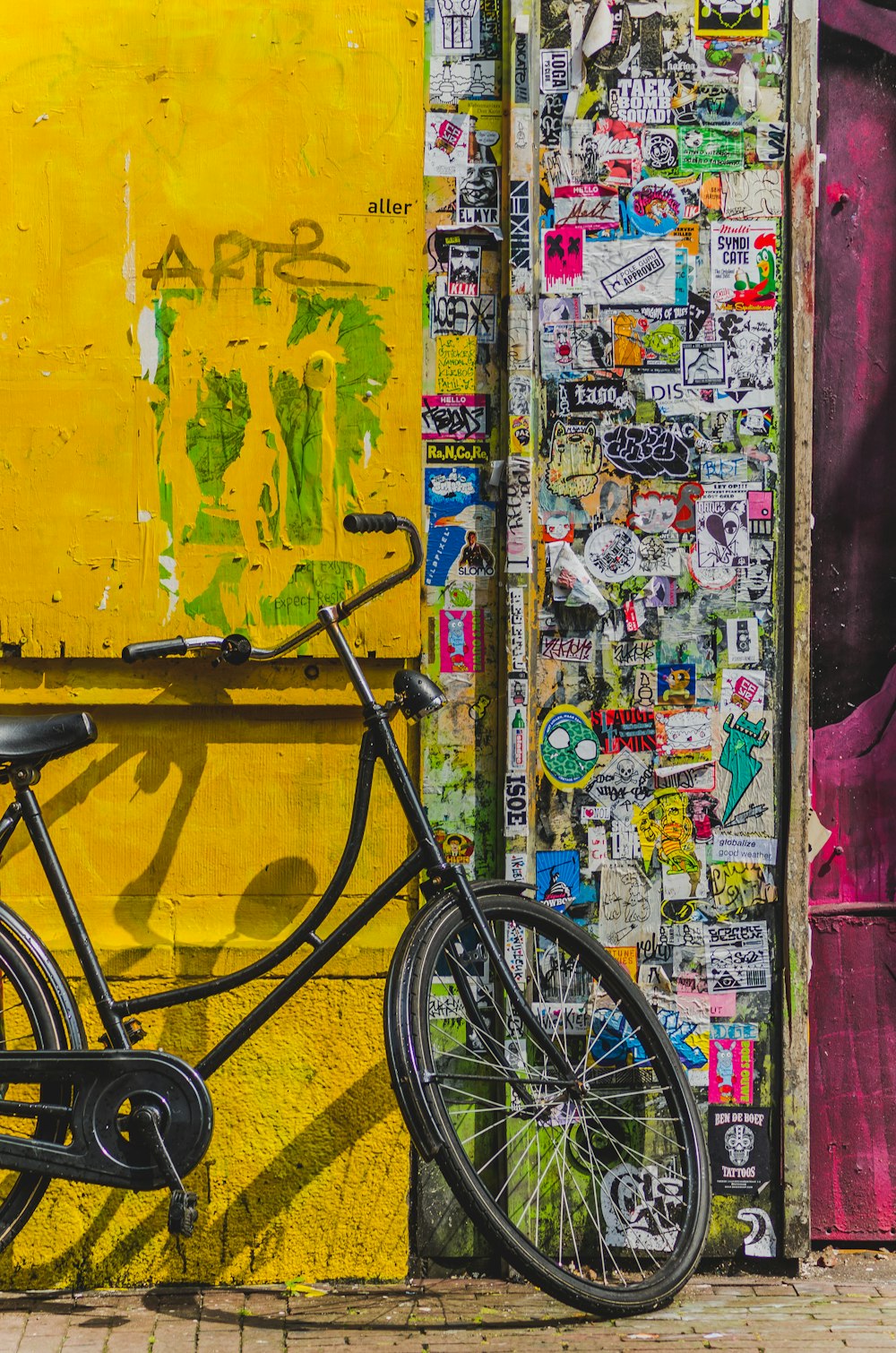 bike parked beside wall full of stickers