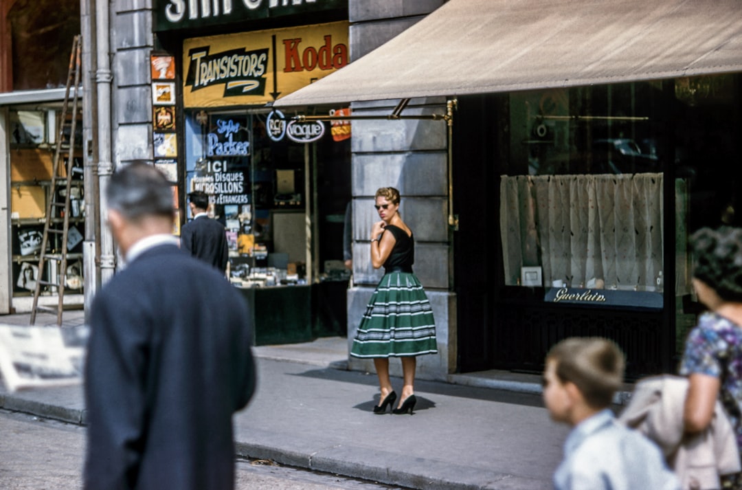 woman looking left while standing beside store along the road, Retro French street
