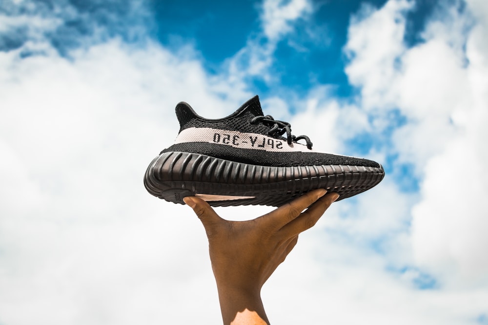 unpaired adidas Yeezy Boost 350 V2 shoe on person's hand