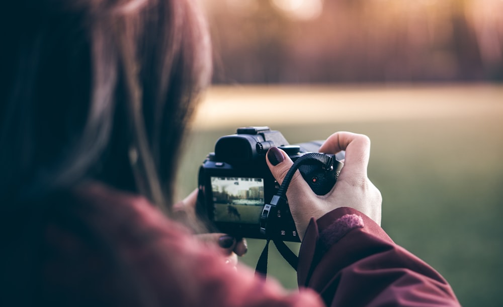 mulher segurando a câmera DSLR preta