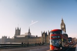 red double-decker bus passing Palace of Westminster, London during daytime