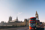 red double-decker bus passing Palace of Westminster, London during daytime