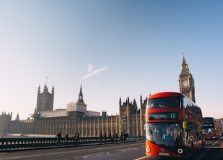 red double-decker bus passing Palace of Westminster, London during daytime