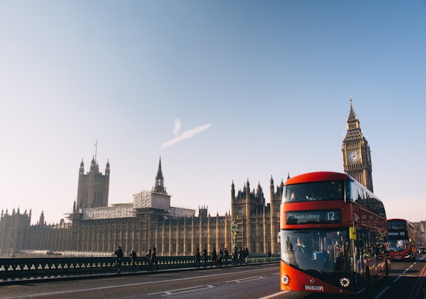 red double-decker bus passing Palace of Westminster, London during daytime