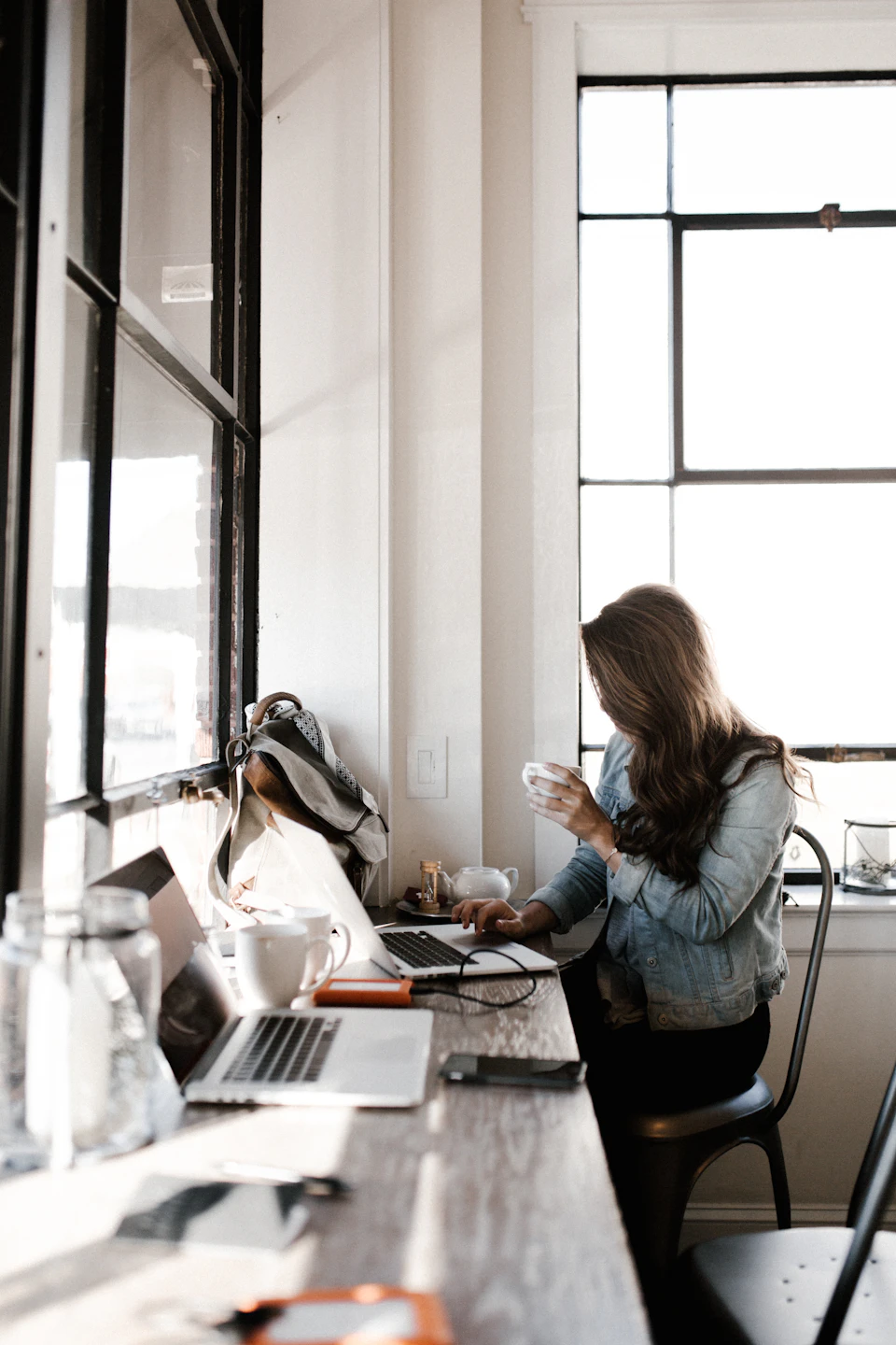 A person working candidly at a laptop by a bright window