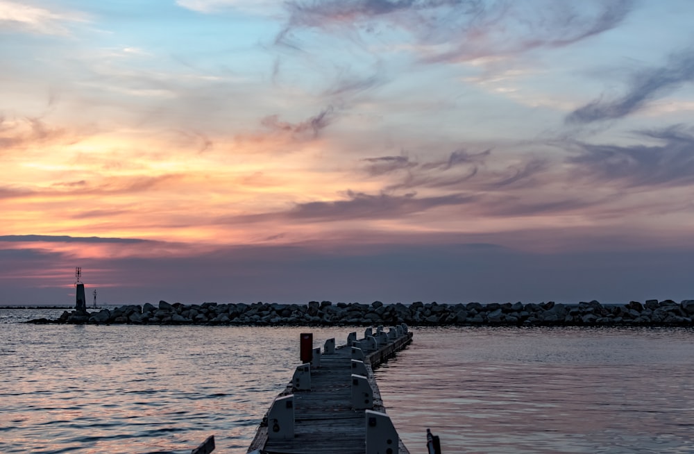 brown wooden dock under gray and orange skies