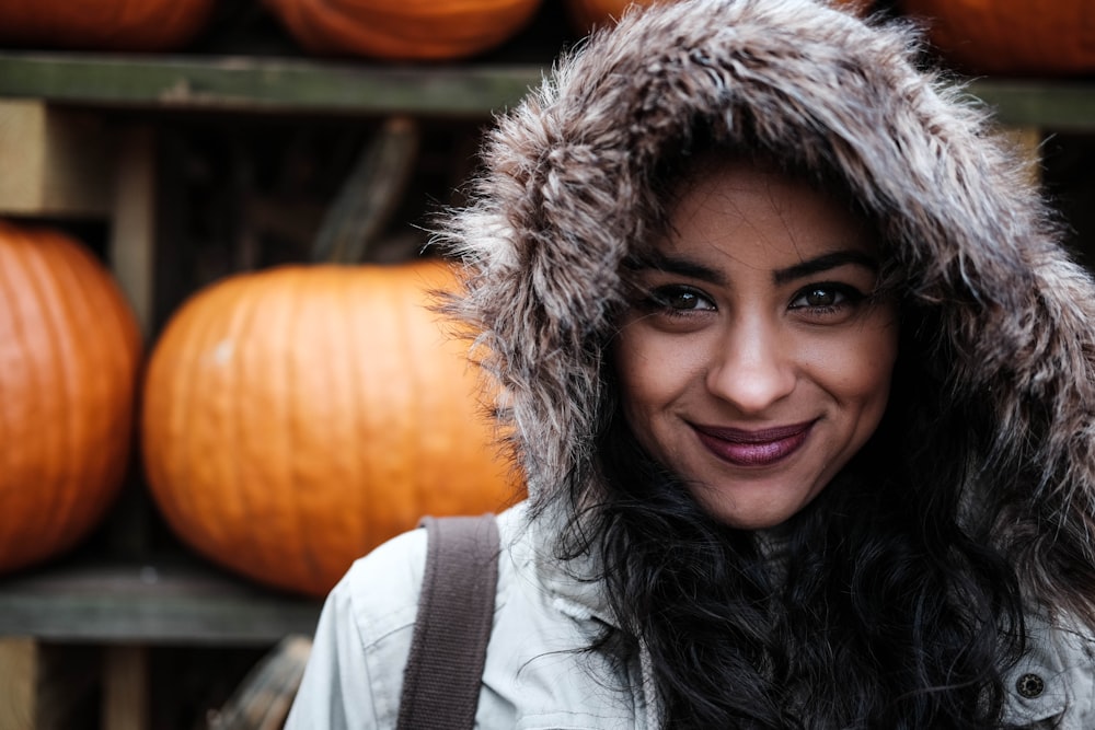 woman in front of orange pumpkin posing