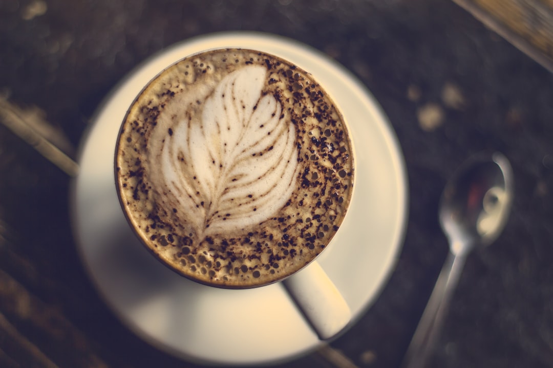 beige coffee with feather art near spoon