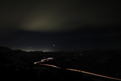 Artistic capture of headlights cutting through early morning fog on a mountain road.